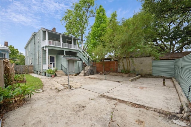rear view of house with a fenced backyard, a chimney, a balcony, and a patio area