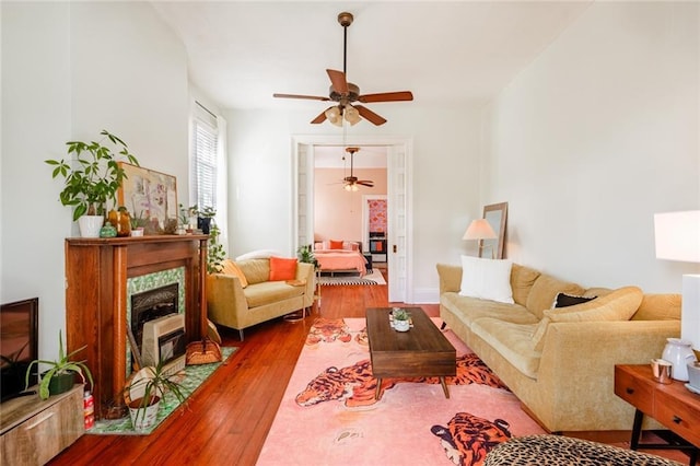 living area featuring hardwood / wood-style floors, ceiling fan, and a high end fireplace