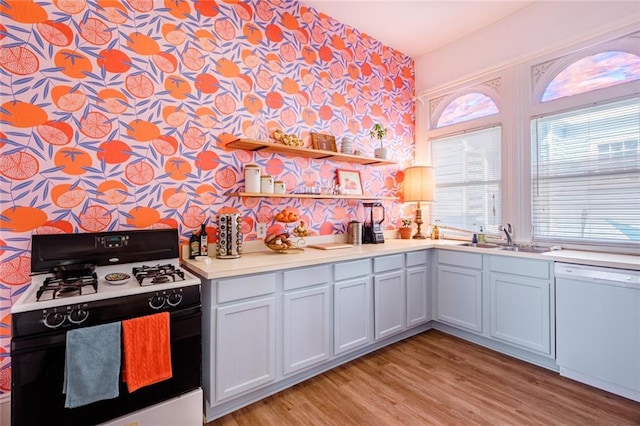 kitchen with range with gas stovetop, dishwasher, wallpapered walls, plenty of natural light, and a sink