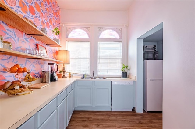 kitchen featuring white appliances, open shelves, a sink, wood finished floors, and light countertops