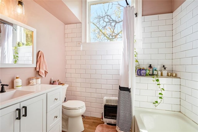 bathroom featuring heating unit, toilet, vanity, and wood finished floors