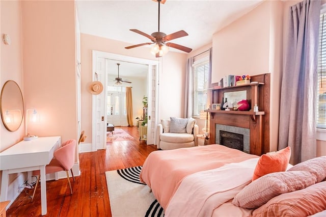 bedroom with hardwood / wood-style floors, a tile fireplace, and baseboards