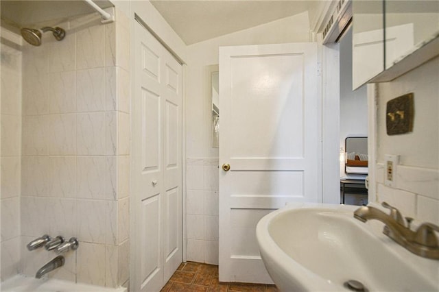 bathroom with a sink, shower / washtub combination, and lofted ceiling