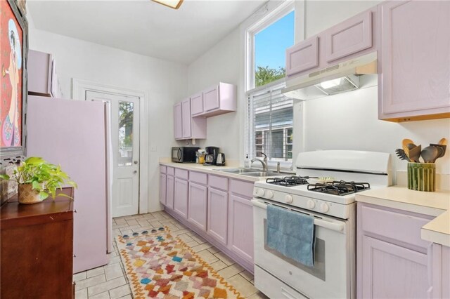 kitchen with white appliances, a sink, under cabinet range hood, and plenty of natural light