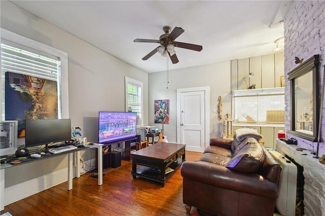 living area with wood finished floors, a ceiling fan, and a desk