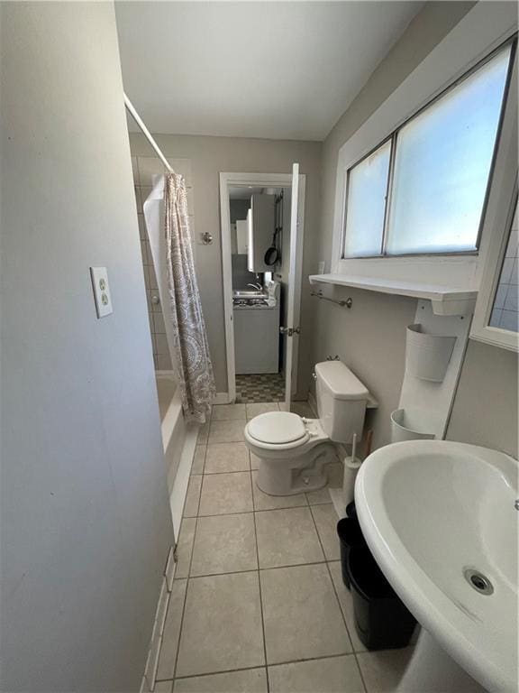 bathroom with tile patterned flooring, toilet, a sink, shower / tub combo, and baseboards