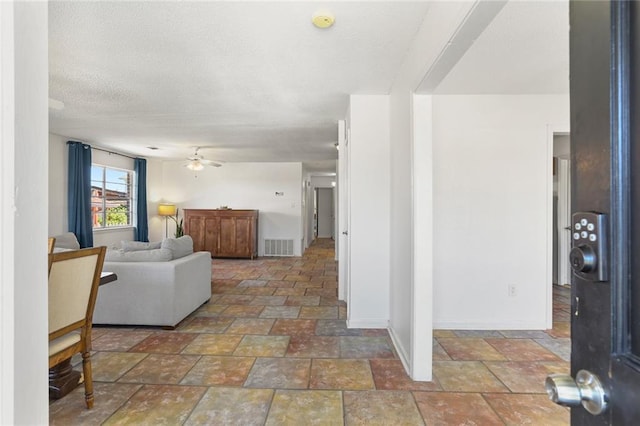 living room with stone finish flooring, ceiling fan, and baseboards