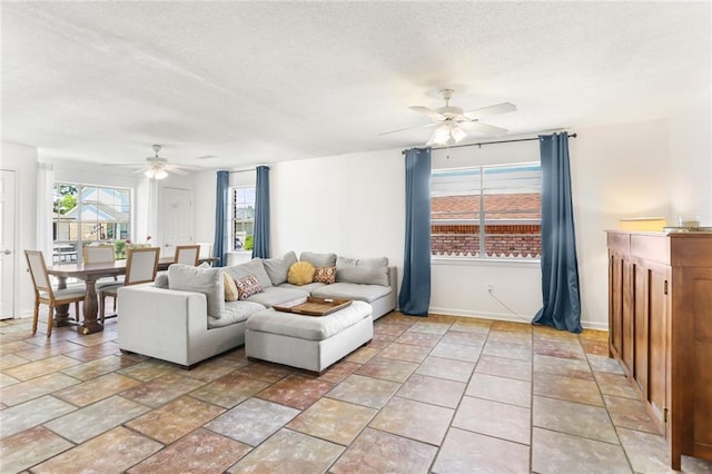 living room featuring ceiling fan, a textured ceiling, and baseboards