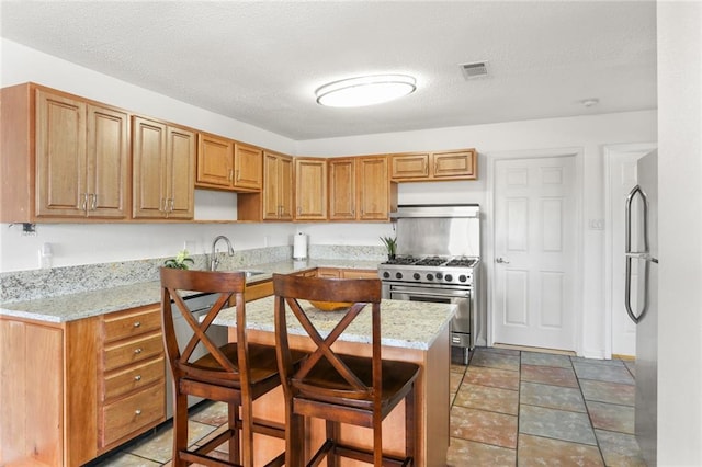 5801 Ruth St, Metairie, LA 70003 - kitchen featuring stainless steel appliances, extractor fan, light stone countertops, a breakfast bar, and a textured ceiling