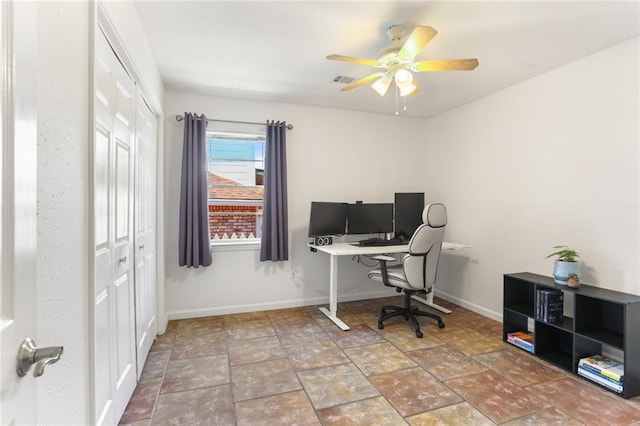 office area with a ceiling fan, stone finish floors, and baseboards