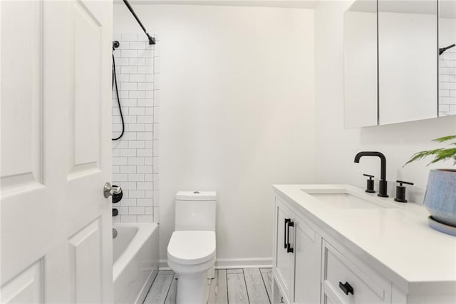bathroom with toilet, vanity, washtub / shower combination, wood finished floors, and baseboards