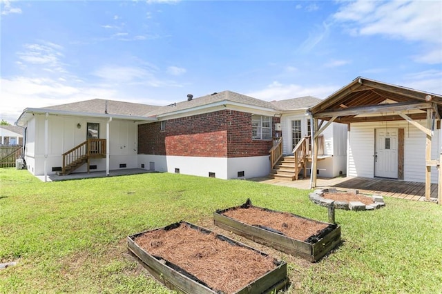 back of house featuring brick siding, a vegetable garden, and a lawn