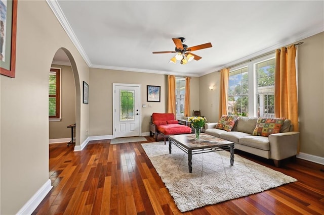 living room with dark wood-type flooring, arched walkways, ornamental molding, a ceiling fan, and baseboards