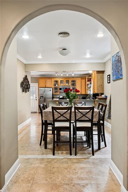 dining area with arched walkways, crown molding, and baseboards