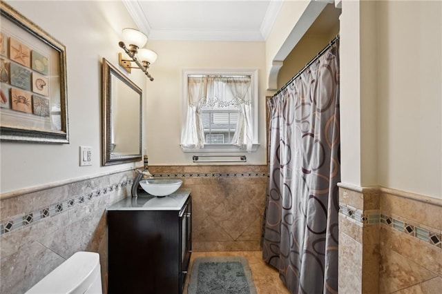 full bath featuring tile walls, wainscoting, toilet, vanity, and ornamental molding