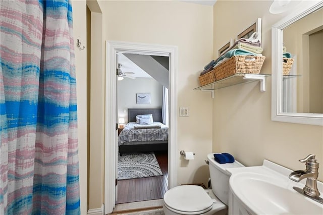 full bath with a sink, toilet, connected bathroom, a shower with curtain, and a ceiling fan