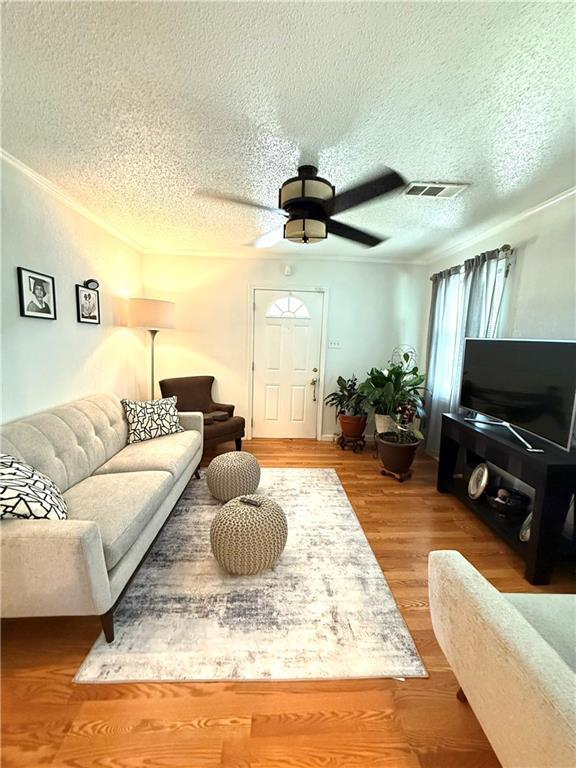 4560 Laine Ave, New Orleans, LA 70126 - living room with a textured ceiling, a ceiling fan, wood finished floors, and crown molding