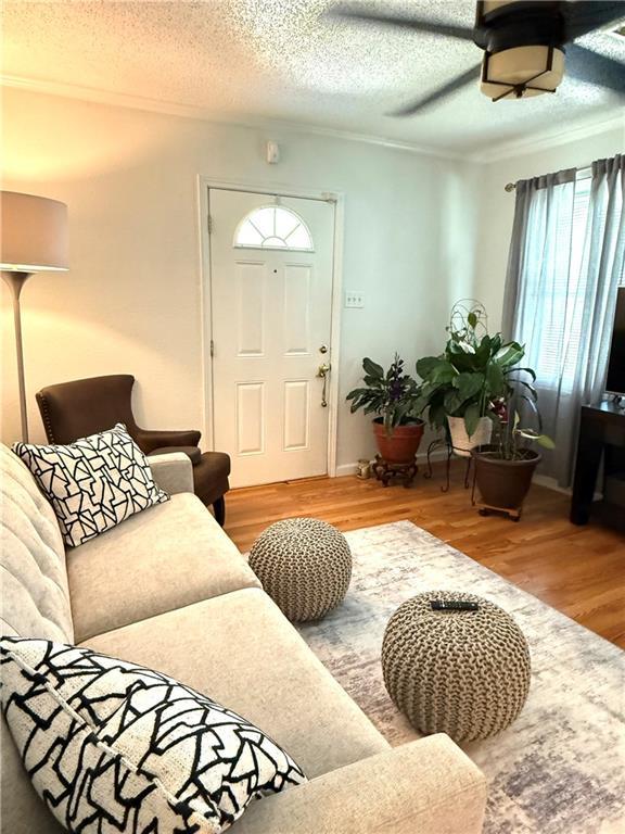 4560 Laine Ave, New Orleans, LA 70126 - living area featuring wood finished floors, ceiling fan, a textured ceiling, and ornamental molding