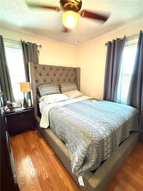 4560 Laine Ave, New Orleans, LA 70126 - bedroom featuring wood finished floors, ornamental molding, a ceiling fan, and a textured ceiling