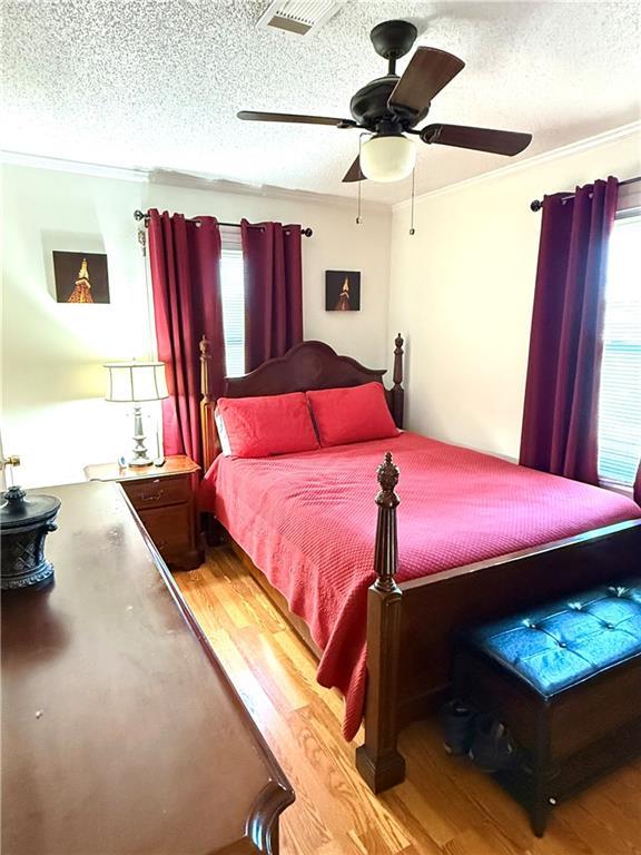 4560 Laine Ave, New Orleans, LA 70126 - bedroom with light wood-style floors, a textured ceiling, ornamental molding, and a ceiling fan
