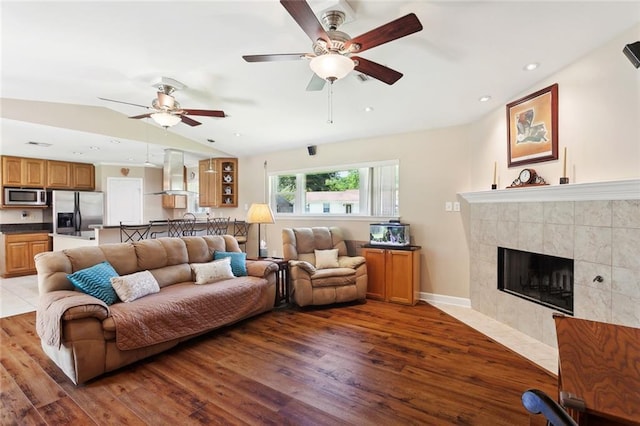 1207 Cousin St, Slidell, LA 70458 - living room with wood finished floors, ceiling fan, vaulted ceiling, a tile fireplace, and recessed lighting