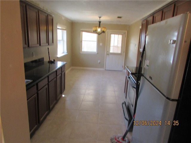 7812 Scottwood Dr, New Orleans, LA 70128 - kitchen with freestanding refrigerator, a chandelier, baseboards, decorative light fixtures, and light tile patterned flooring