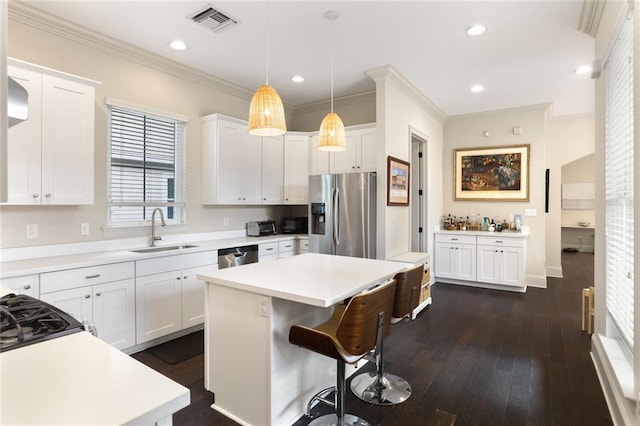 110 Sharon Dr, New Orleans, LA 70124 - kitchen featuring appliances with stainless steel finishes, a sink, a center island, white cabinets, and ornamental molding
