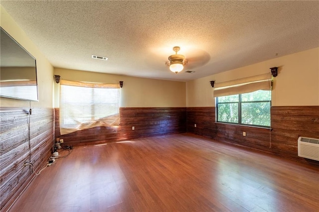 20408 Smith Rd, Covington, LA 70435 - spare room featuring a wainscoted wall, wood walls, plenty of natural light, wood finished floors, and a textured ceiling
