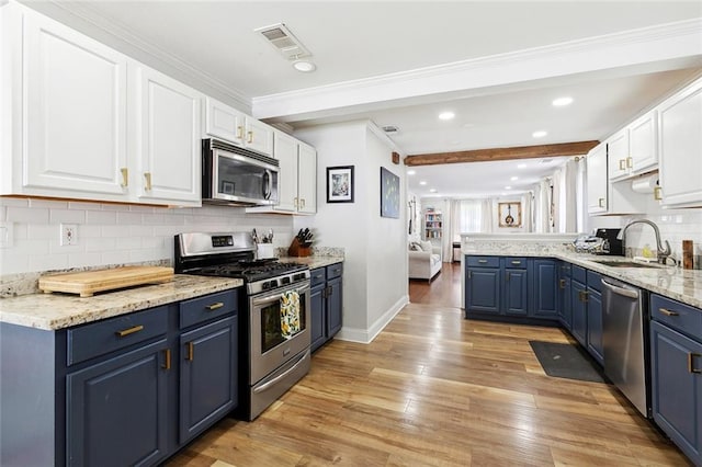 kitchen with stainless steel appliances, blue cabinets, a sink, white cabinetry, and recessed lighting