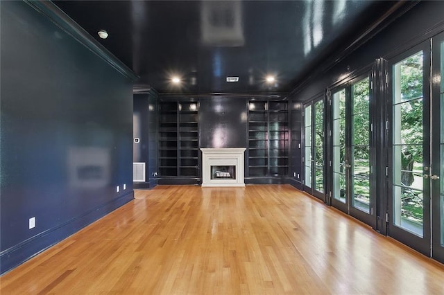 1215 Exposition Blvd, New Orleans, LA 70118 - unfurnished living room with ornamental molding, wood finished floors, built in shelves, a glass covered fireplace, and baseboards
