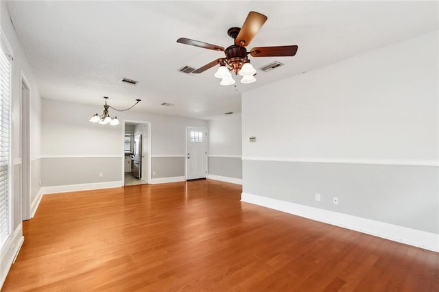 unfurnished room with a chandelier, a ceiling fan, light wood-style floors, and baseboards