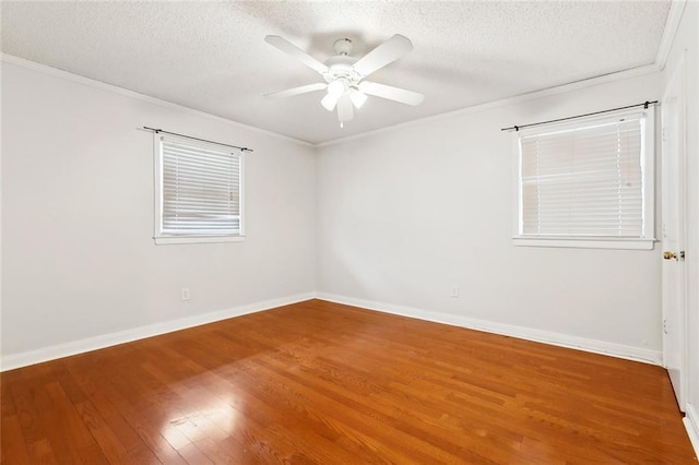 spare room with wood finished floors, a ceiling fan, a textured ceiling, ornamental molding, and baseboards