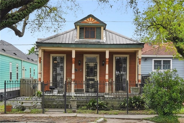 view of front of house with covered porch, a fenced front yard, and metal roof