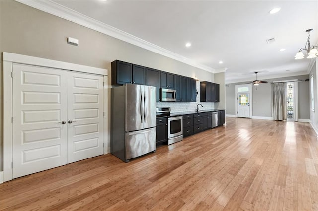 kitchen featuring stainless steel appliances, ornamental molding, ceiling fan, tasteful backsplash, and light wood-type flooring