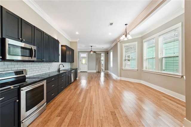 kitchen with stainless steel appliances, ornamental molding, a sink, decorative backsplash, and light wood-style flooring