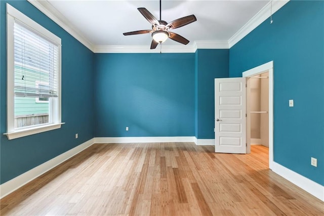 spare room featuring ceiling fan, wood finished floors, crown molding, and baseboards