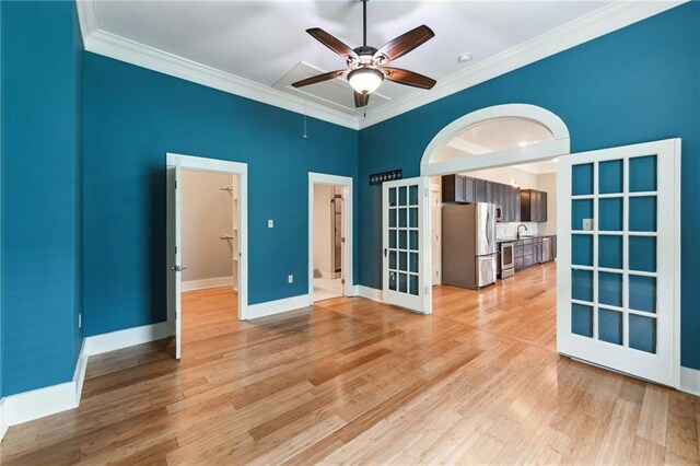 unfurnished room with crown molding, a ceiling fan, french doors, light wood-style floors, and baseboards