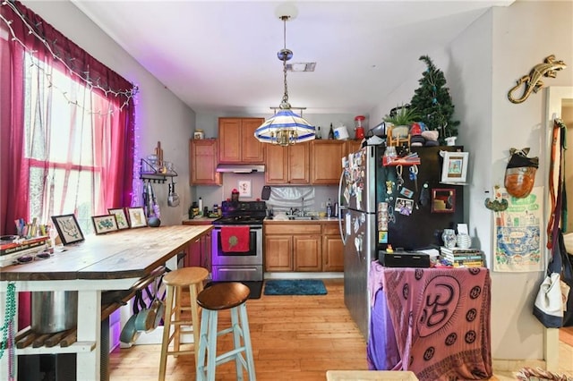 kitchen with stainless steel electric range oven, light wood-style floors, under cabinet range hood, and plenty of natural light