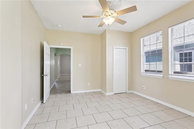 3725 Clermont Dr, New Orleans, LA 70122 - unfurnished bedroom with arched walkways, baseboards, light tile patterned flooring, a closet, and a ceiling fan