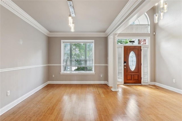 foyer featuring decorative columns, hardwood / wood-style floors, baseboards, and crown molding