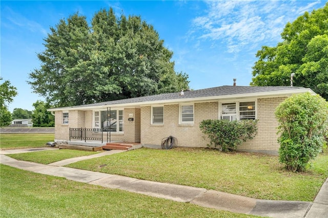 single story home featuring brick siding, a front lawn, and a deck