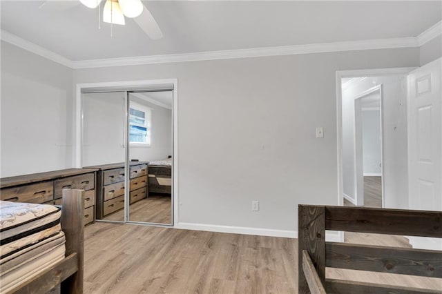 unfurnished bedroom featuring ornamental molding, light wood-type flooring, baseboards, a closet, and a ceiling fan
