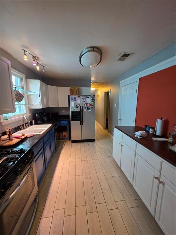 1309 Independence St, New Orleans, LA 70117 - kitchen featuring stainless steel appliances, a sink, dark countertops, white cabinets, and light wood-style floors