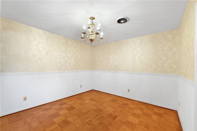 spare room with a chandelier and baseboards