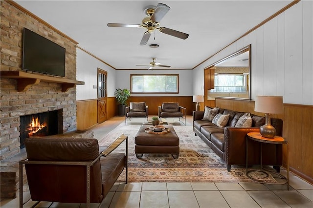 living room with ornamental molding, wood walls, wainscoting, a fireplace, and a ceiling fan