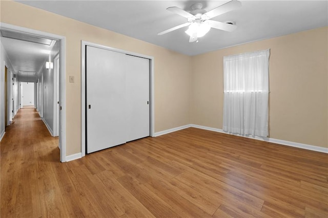 unfurnished bedroom featuring light wood-style floors, baseboards, a closet, and ceiling fan