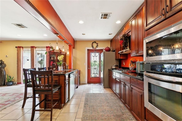 402 28th St, New Orleans, LA 70124 - kitchen featuring dark countertops, appliances with stainless steel finishes, light tile patterned floors, a breakfast bar area, and recessed lighting