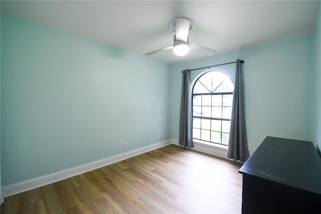 unfurnished room featuring wood finished floors, a ceiling fan, and baseboards