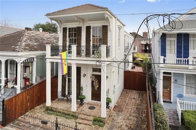 2026 Camp St, New Orleans, LA 70130 - shotgun-style home with a fenced front yard, a porch, a balcony, and a gate