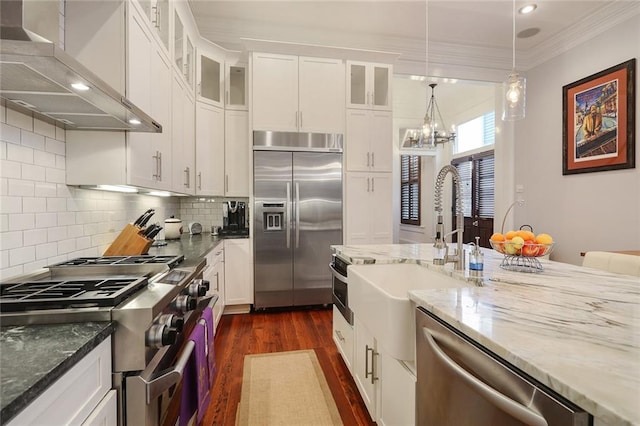 2026 Camp St, New Orleans, LA 70130 - kitchen with premium appliances, wall chimney exhaust hood, a sink, dark wood-style flooring, and a chandelier